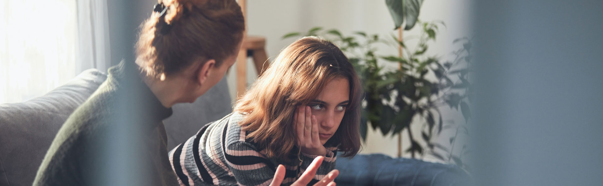 An adult taking to a yong person who doesn't look very happy. Both are sitting and it feels intense