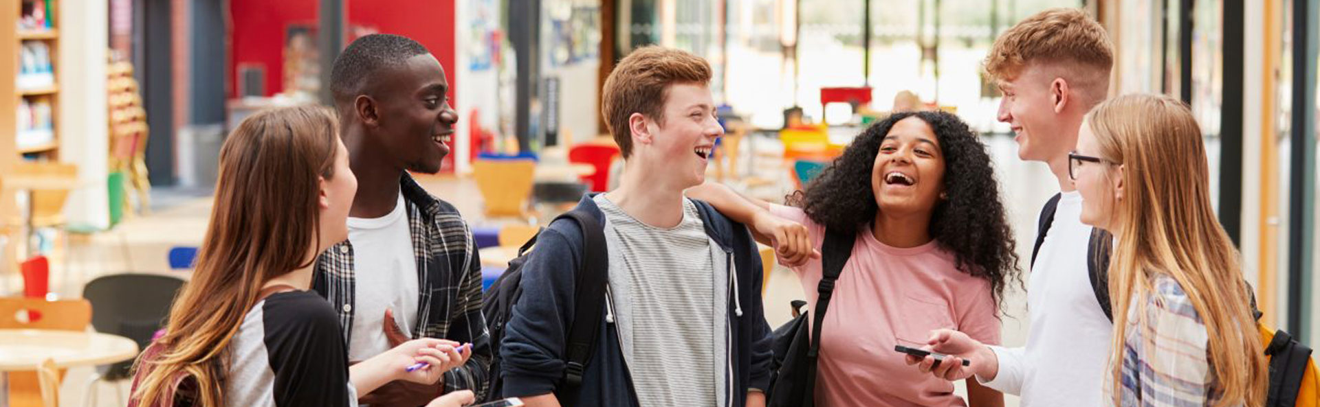 Students standing laughing in an empty classroom
